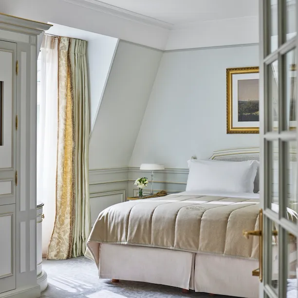 Bedroom of a junior suite with light green and beige tones at Le Meurice, Paris.