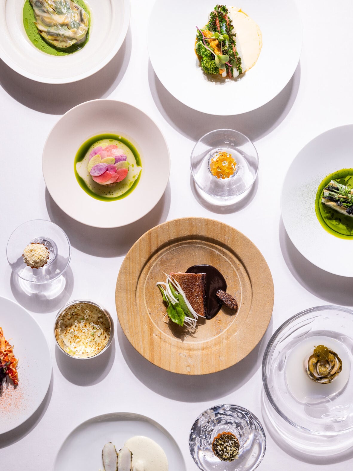 Top shot of a white table with many delicacies served in various plates at restaurant Le Meurice Alain Ducasse.  