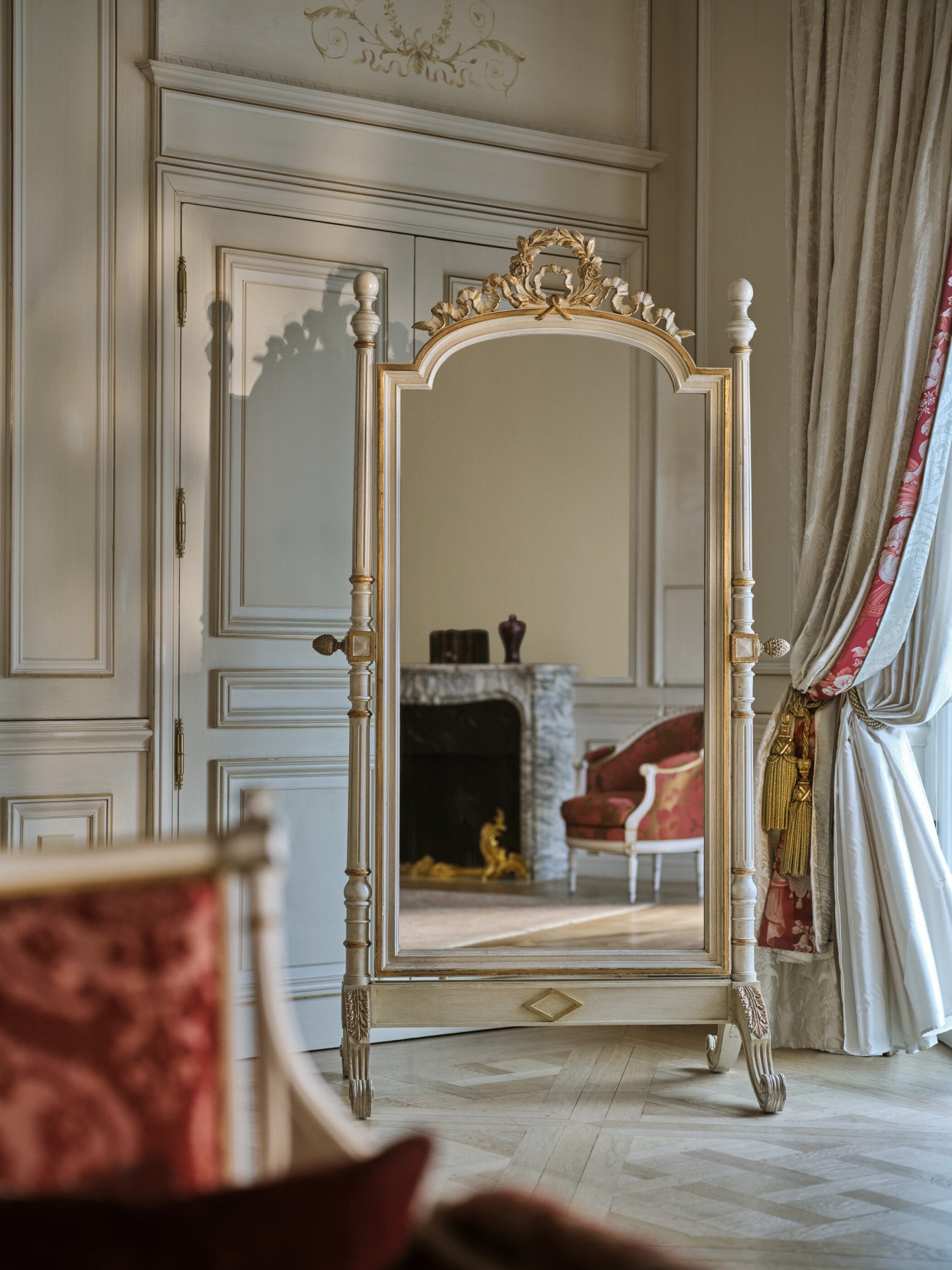 Reflect on the mirror, of the Presidential Suite Dali, of the chair next to the fireplace with decorations on the top, at Le Meurice, Paris
