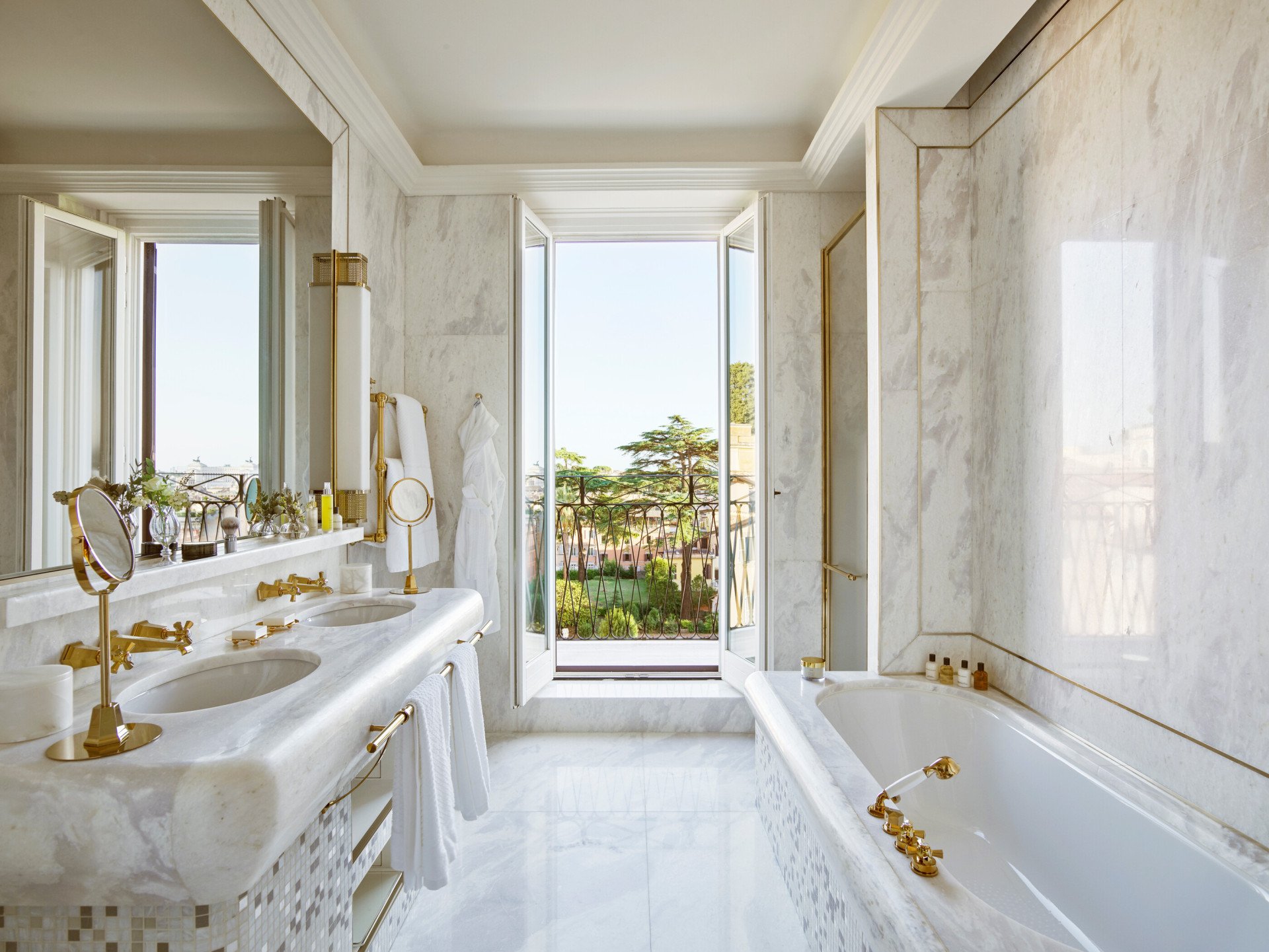 White marble bathroom of Presidential Suite with double sinks, bathtub and window with view of Rome at Hotel Eden