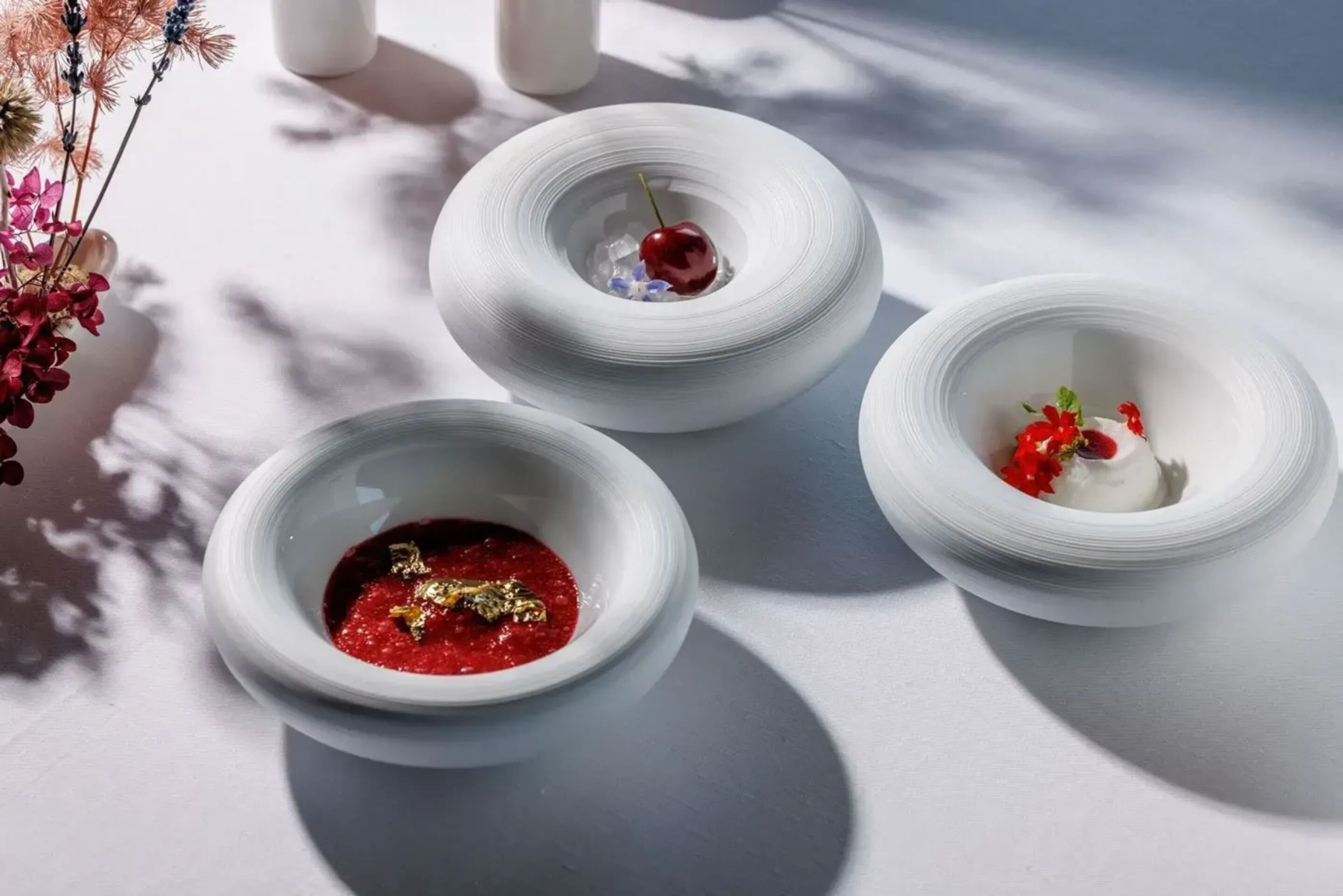 Three round dishes with the various elements of the dessert Donkey milk, cherry and roses from La Terrazza menu