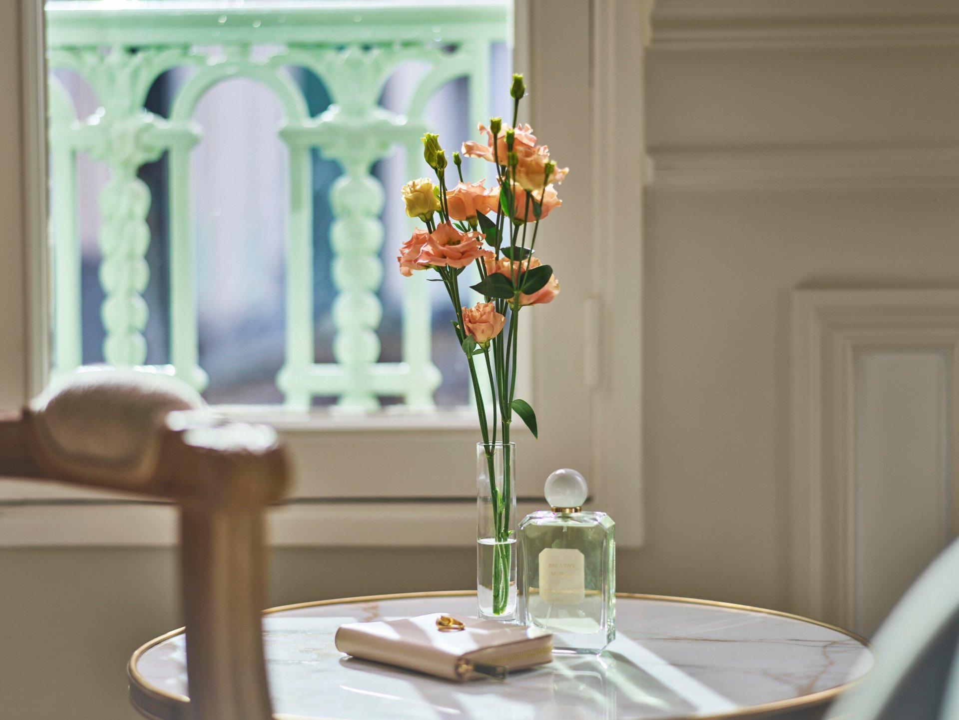 Flowers, a bottle of perfume and a clutch placed on a low marble table in a superior room. At Le Meurice, Paris.