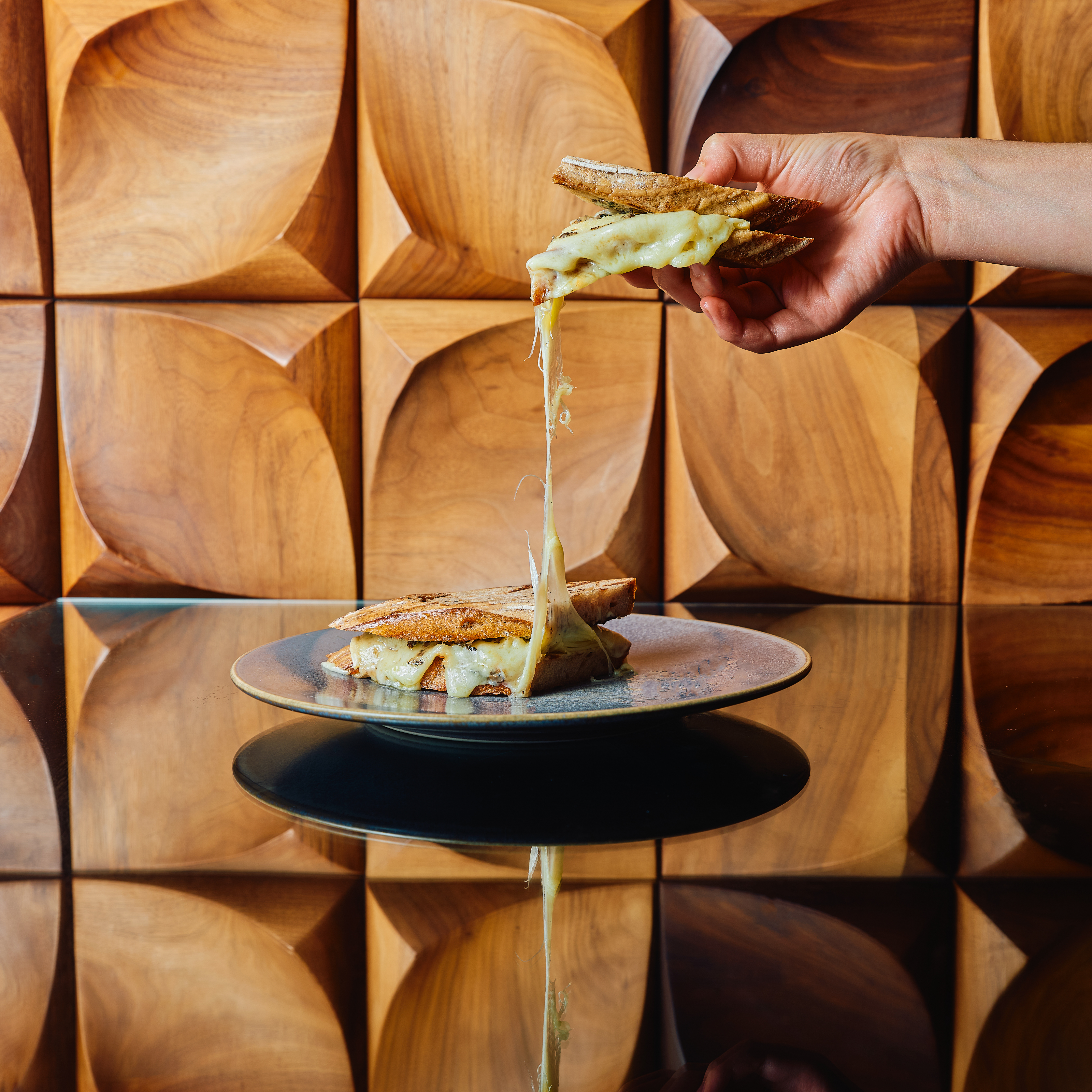 Cheese and truffle toasted sandwich halves on grey plate, pulled apart by hand