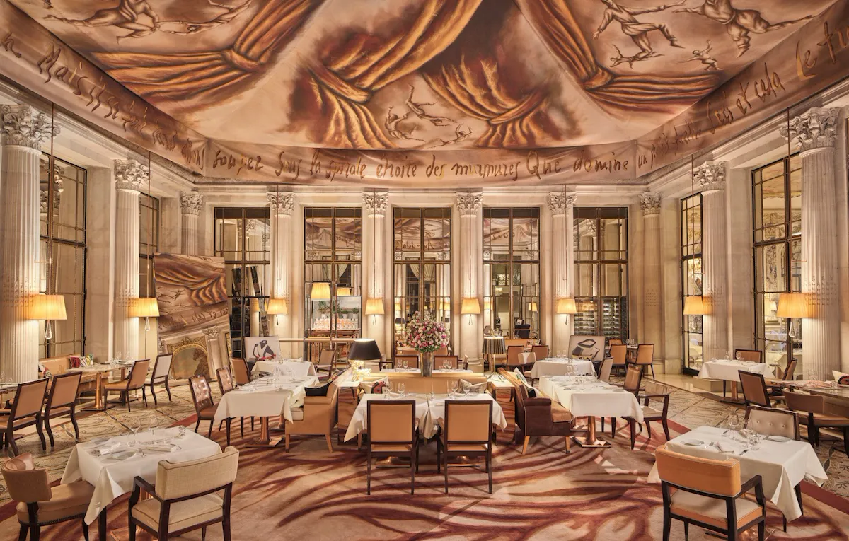 Large view on the restaurant Le Dali with all the dining furnitures, the mirror, the carpet and the painting on the ceiling, at Le Meurice, Paris