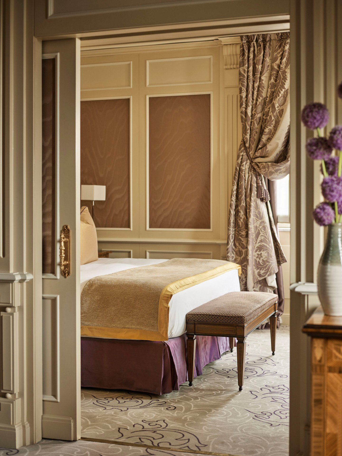 Ambassador Suite Bedroom Snippet revealing the king sized bed and a bouquet of purple flowers