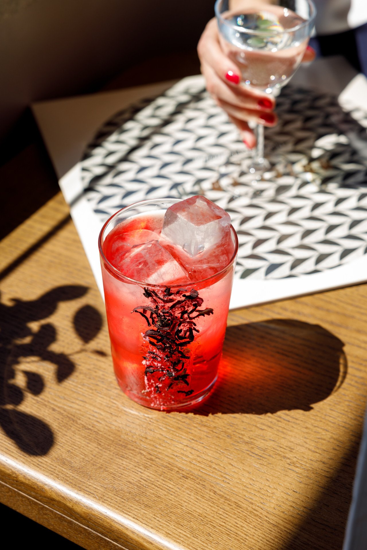 Red coloured cocktail on the rocks on wooden counter at Il Giardino Bar at Hotel Eden, Rome
