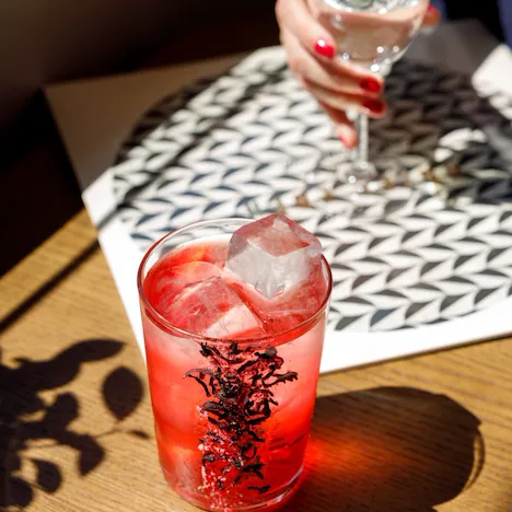 Red coloured cocktail on the rocks on wooden counter at Il Giardino Bar at Hotel Eden, Rome