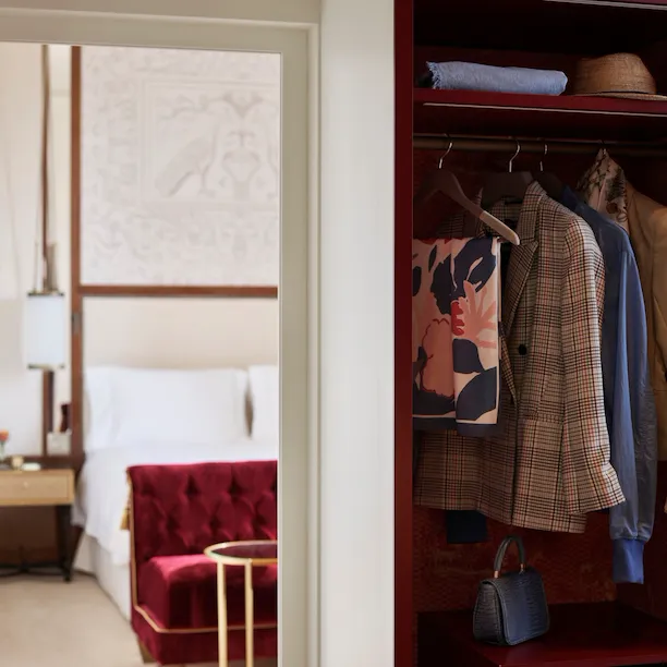 Wardrobe with clothes and bedroom in the background at Dolce Vita Suite at Hotel Eden, Rome
