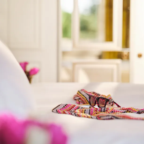 Scarf and sunglasses on bed in a room at Hotel Eden Rome