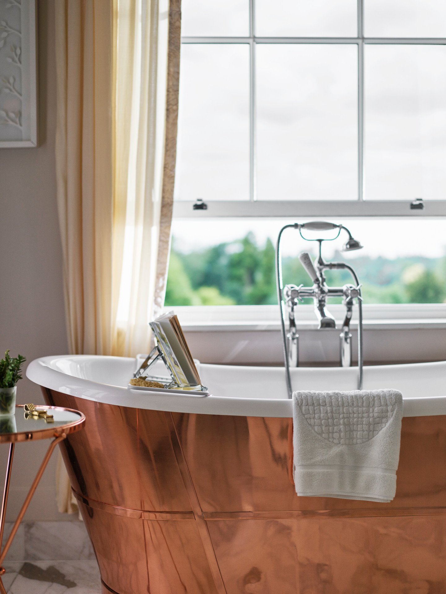 Copper bathtub with window nearby open with countryside view of Coworth Park, Ascot