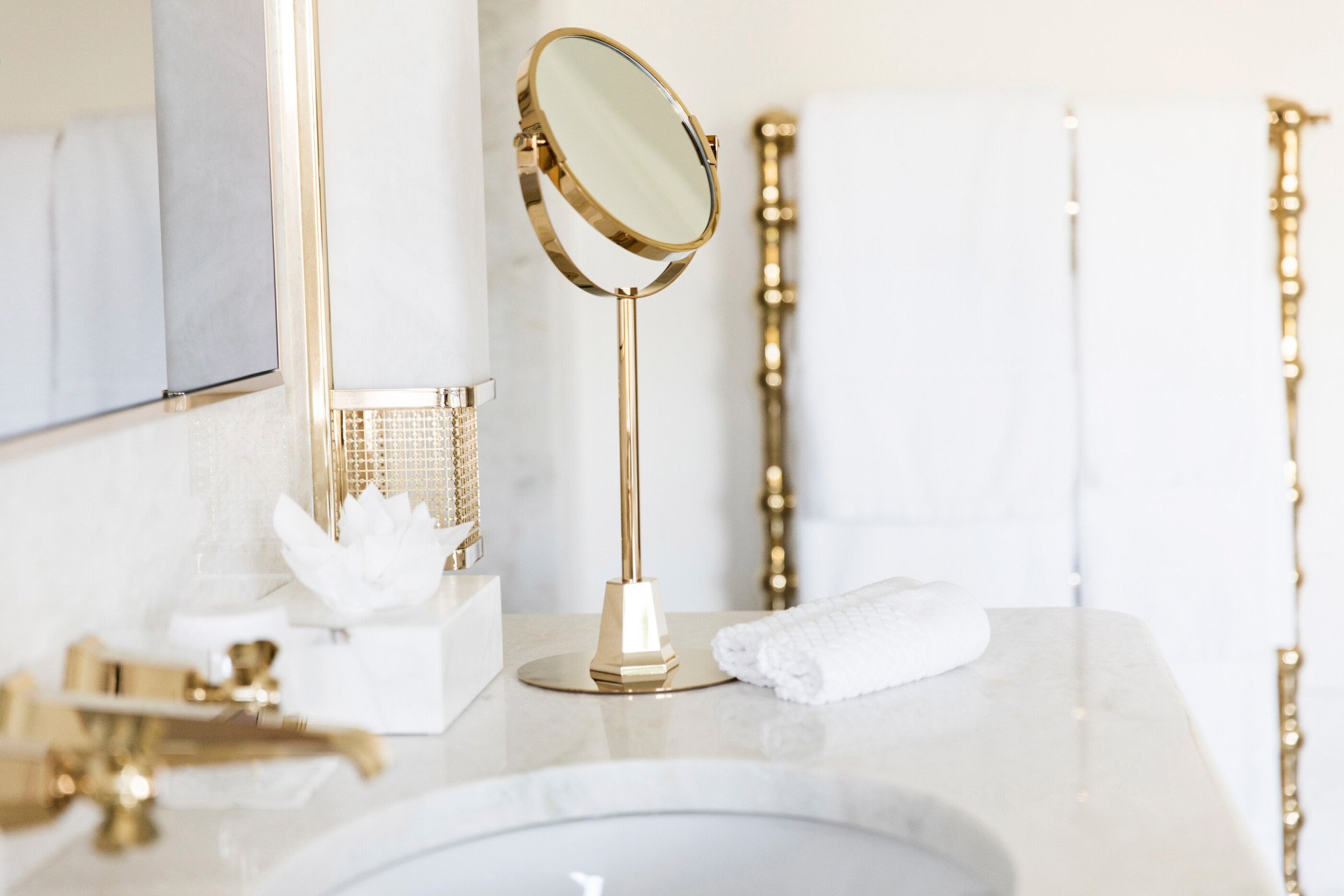 Bathroom detail with vanity mirror, towels and white marble sink at Hotel Eden, Rome