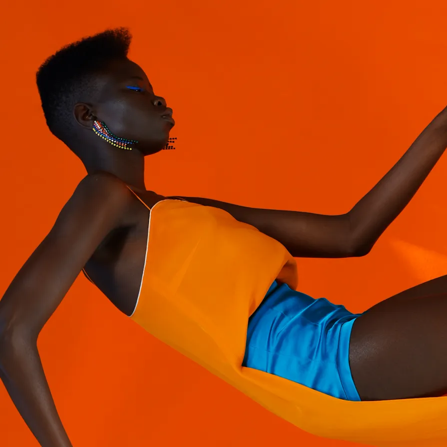 One of photographer Zach Gold's works depicting a woman wearing an orange top and electric blue shorts against an orange background.