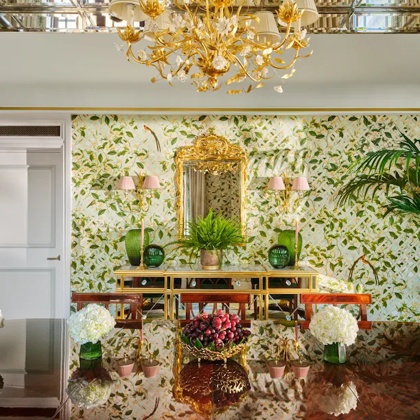 Elegant chandelier illuminates a lush themed dining room with floral wallpaper and lush greenery