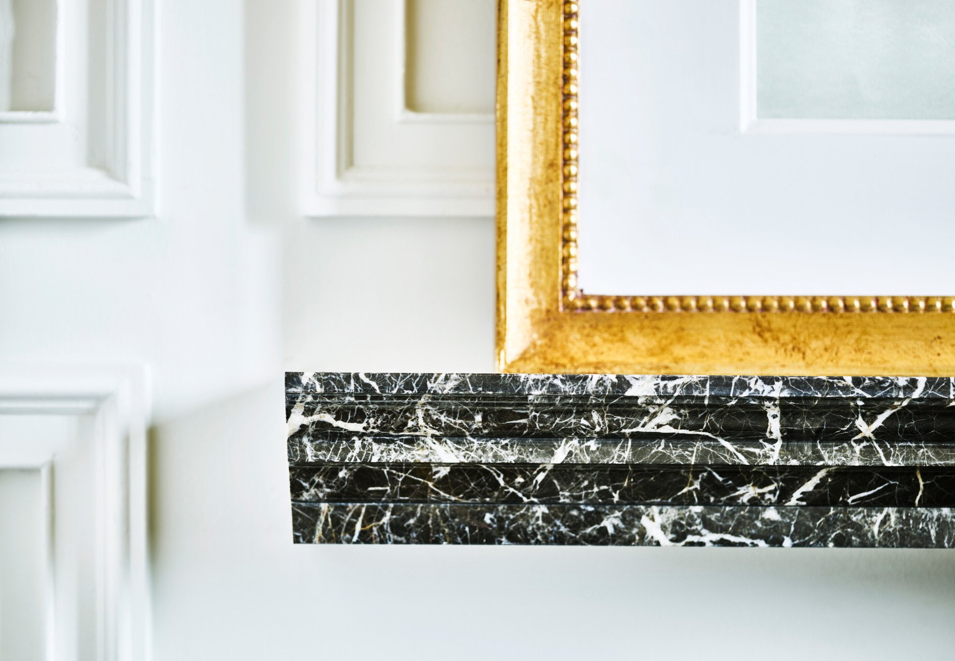 Detail of black marble with white veins shelf and mirror with golden frame at Hotel Eden, Rome