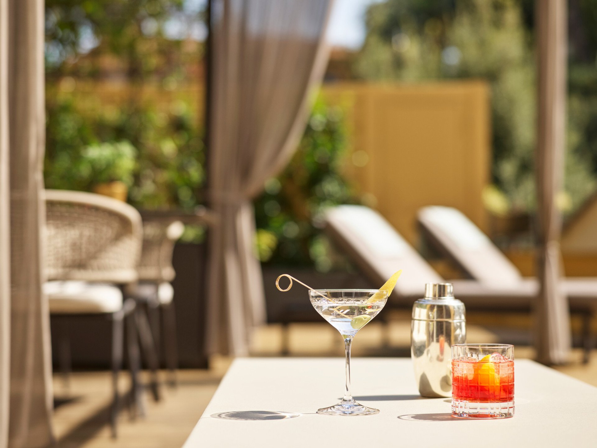 Martini and Negroni cocktails with sunbeds in the background at sunny Aurora Terrace Suite at Hotel Eden, Rome