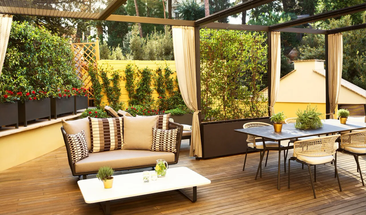 Sunny terrace with couch, dining table and chairs at Aurora Terrace Suite at Hotel Eden, Rome