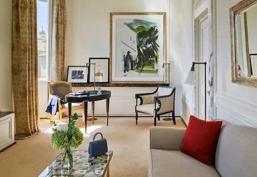 Living room of Prestige suite with sofa, desk, armchair, paintings and view of Rome at Hotel Eden