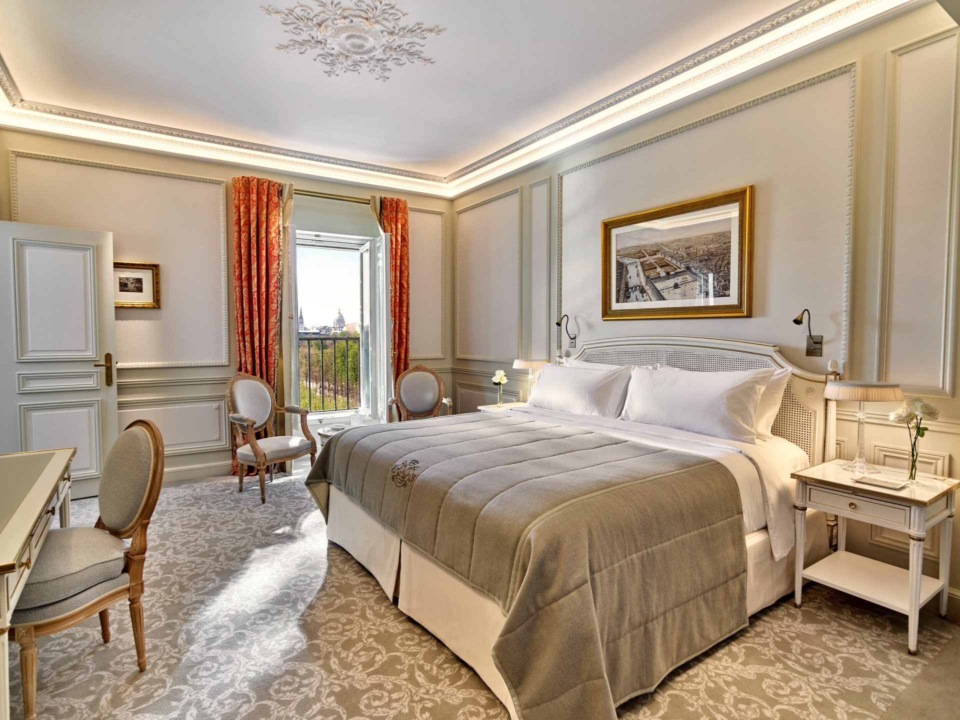 Luxurious hotel room with a plush bed, elegant chairs, and an open window with a scenic view. The room has ornate decor and warm, inviting tones.